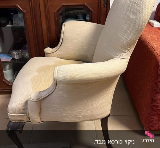 כיסא עם כתם על המושב, ליד שטיח פסים